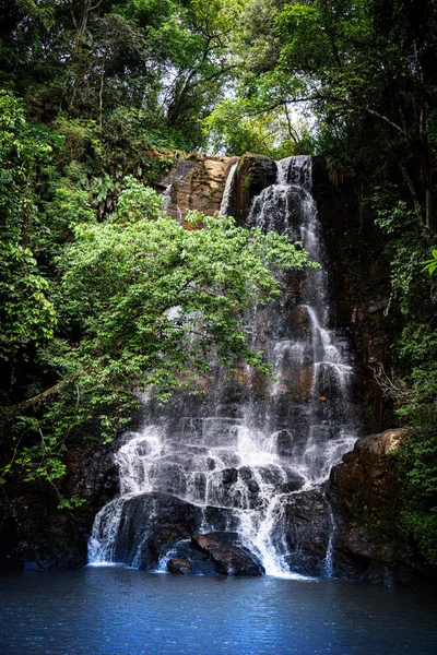Bonita cascada a través de la vegetación verde con rocas y un pequeño lago en Brasil. — Foto de Stock
