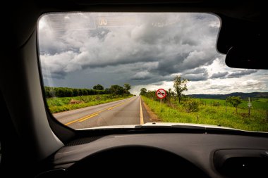 Brezilya 'da asfalt bir yol, yeşil bir tarla ve ağır bulutlar.