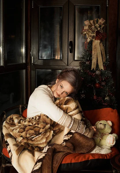 Девочка согревается холодной зимой теплым одеялом на уютном диване у себя дома. Уставшая больная девушка страдает от лихорадки, гриппа, прострации. Милая девушка с гриппом сидит дома, чтобы побаловать себя. — стоковое фото