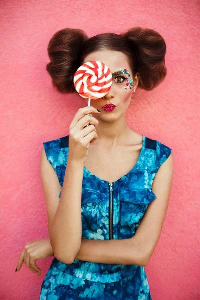 Estudio primer plano retrato colorido de la joven sexy chica de moda posando sobre fondo de pared rosa en traje de estilo de verano con piruleta rosa con vestido azul. Imagen creativa de chica bonita con piruleta . — Foto de Stock