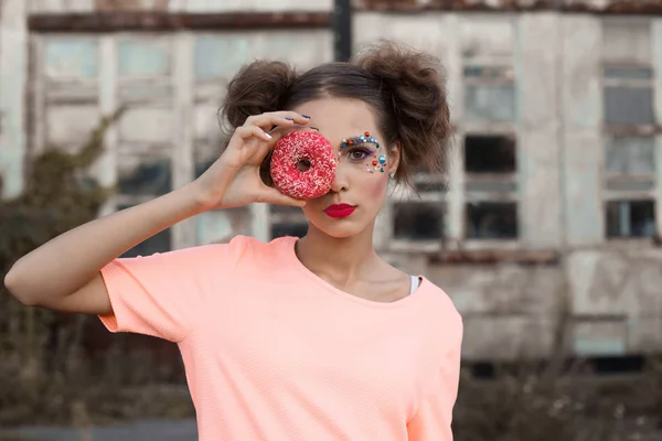 Primer plano retrato de la mujer joven que cubre sus ojos con donuts sobre fondo blanco.Belleza modelo chica tomando dulces y coloridos donuts.Funny alegre Vogue mujer de estilo con dulces — Foto de Stock