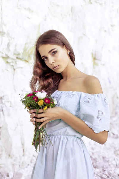 Retrato de menina bonita segurando flores. Imagem de menina bonito com buquê de flores no verão . — Fotografia de Stock