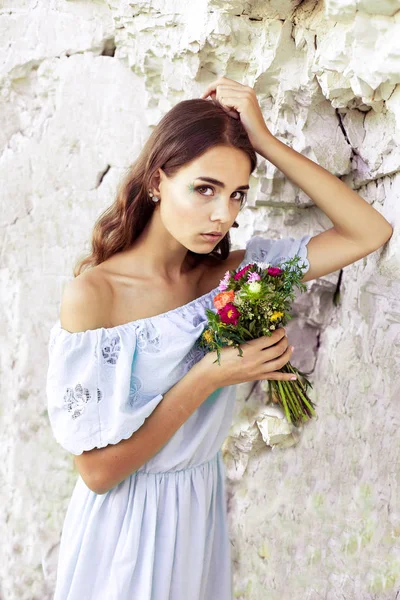 Retrato de menina bonita segurando flores. Imagem de menina bonito com buquê de flores no verão . — Fotografia de Stock