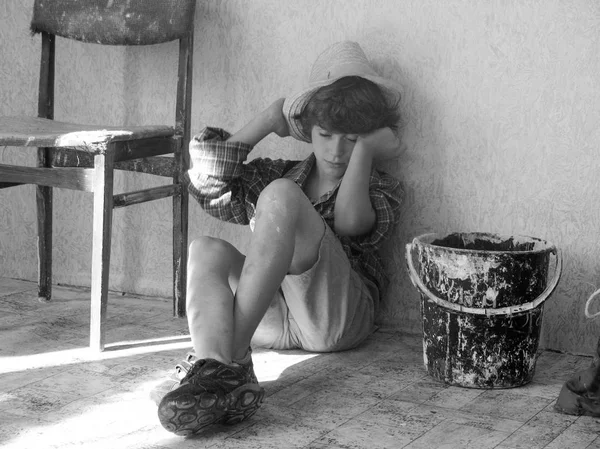 Child labour concept. Tired boy painter is very tired after work.Tired schoolchild in shirt sleeping on the floor. Black and white photo. Children worker. Stop child labour — Stock Photo, Image