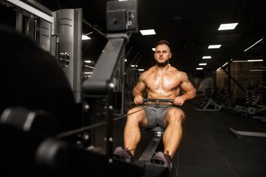 Geceleri karanlık spor salonunda çalışan bir adam. Kürek sporu.