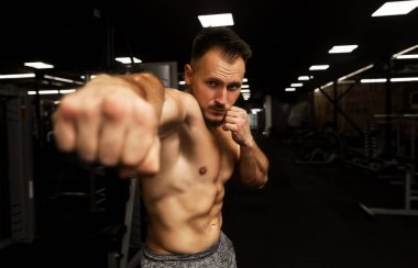 Genç, sakallı, yakışıklı, çıplak vücutlu, spor salonunda tek başına antrenman yapan bir adam. Ot Tekmeleyen El.