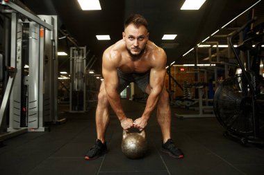 Kettlebell 'i tutan ve popüler karanlık salıncakta sallanan güçlü, yakışıklı sakallı adam. Spor aşktır..