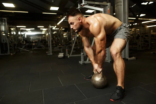 Hombre barbudo guapo fuerte sosteniendo pesas y haciendo columpios delanteros de mancuerna en el popular gimnasio oscuro. Todo lo que necesitas es deporte. . — Foto de Stock