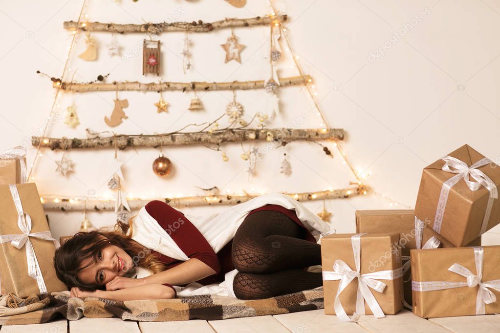 Adorable cute ittle girl sleeping under the Christmas tree by a many Christmas gifts on Christmas eve. WISHES COME TRUE.