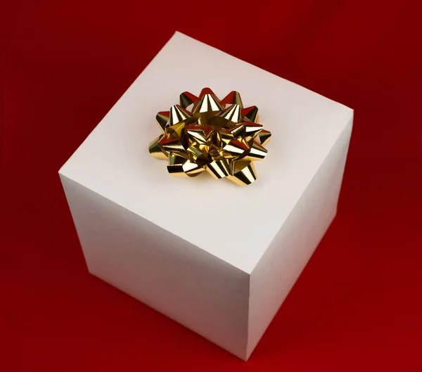 Kırmızı zemin üzerine altın şerit yay ile hediye kutusu — Stok fotoğraf