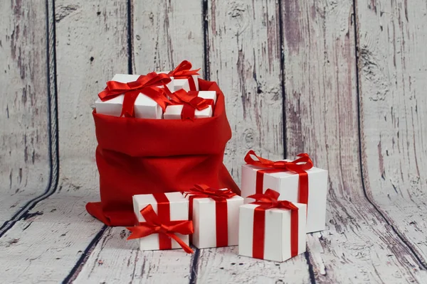 Ahşap arka plan üzerinde kırmızı kurdele fiyonklu hediye kutusu