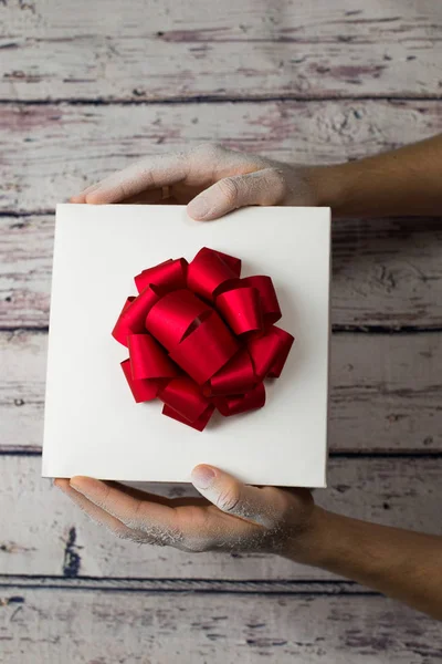 Mann hält weißen Geschenkkarton auf Holz Hintergrund — Stockfoto