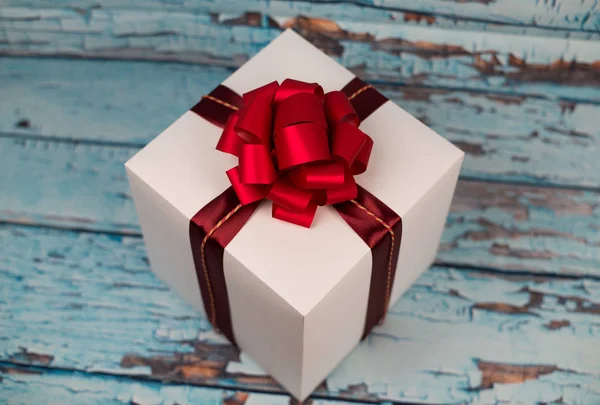 Caja de regalo con lazo rojo sobre fondo de madera — Foto de Stock