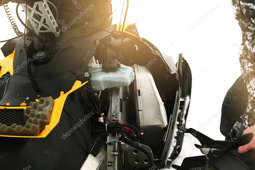 Driver repairing a broken snowmobile.