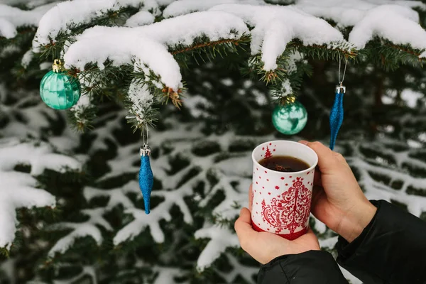 Uma menina segurando uma xícara de chá quente ao lado de uma árvore. Inverno. Natal. . — Fotografia de Stock