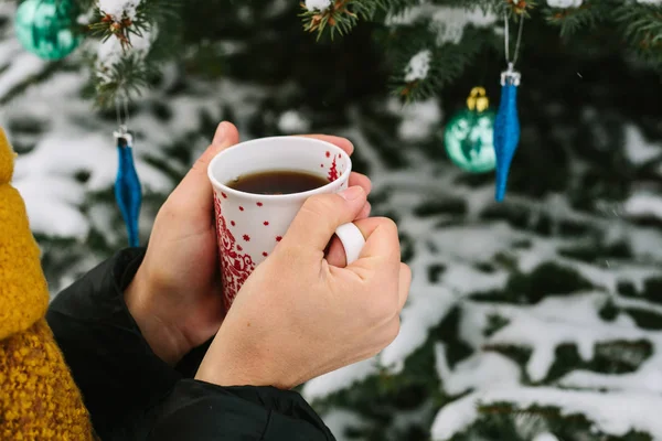 A girl holding a cup of hot tea next to a tree. Winter. Christmas. — Stock Photo, Image