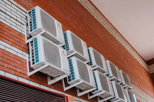 a lot of air conditioners on a brick wall