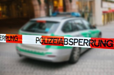 Olay yerinde polis teyp. Polis teyp, bir polis arabasının arka plan bulanık üzerinde odaklanmaktadır. Alman polisi.