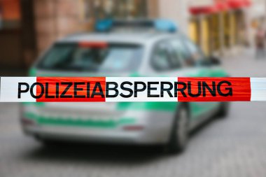 Olay yerinde polis teyp. Polis teyp, bir polis arabasının arka plan bulanık üzerinde odaklanmaktadır. Alman polisi.