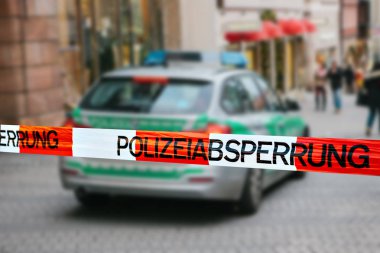 Olay yerinde polis teyp. Polis teyp, bir polis arabasının arka plan bulanık üzerinde odaklanmaktadır. Alman polisi.