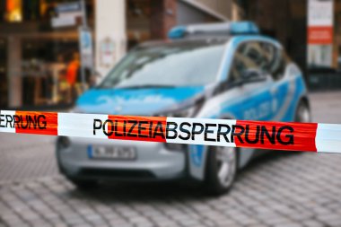 Olay yerinde polis teyp. Polis teyp, bir polis arabasının arka plan bulanık üzerinde odaklanmaktadır. Alman polisi.