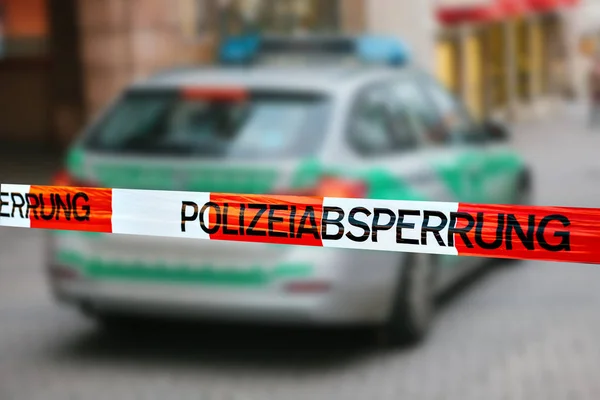 Police tape at the crime scene. Focus on the police tape, a police car on blurred background. german police. — Stock Photo, Image