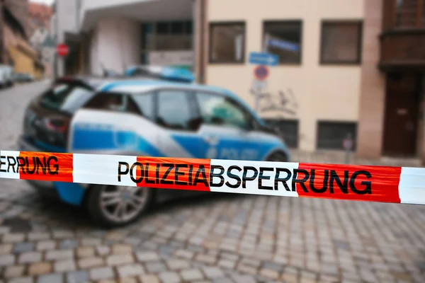 Polisen tejp på brottsplatsen. Fokusera på polisen bandet, en polisbil på suddig bakgrund. tysk polis. — Stockfoto