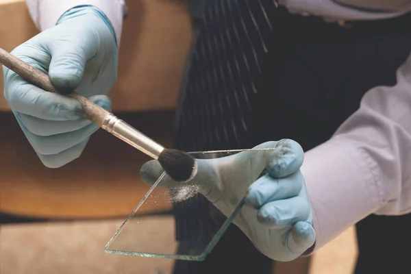 Experto forense de la policía tomando huellas dactilares del vidrio con un cepillo especial. La investigación del crimen. Búsqueda de pruebas . — Foto de Stock