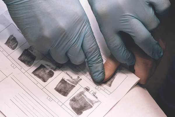 Офицер полиции снимает отпечатки пальцев подозреваемого в преступлении. Расследование преступления. Виновен в правонарушении по требованию полицейского . — стоковое фото