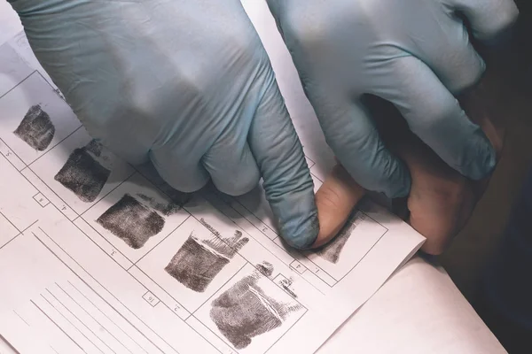 El oficial de policía toma una huella del sospechoso en el crimen. Investigación del crimen. Culpable de un delito está sujeto a la petición de un policía . — Foto de Stock