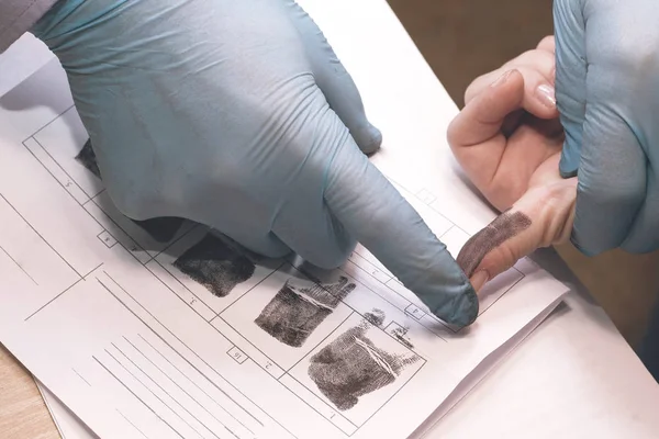 Расследование преступления. Инспектор снимает отпечатки пальцев подозреваемого. . — стоковое фото