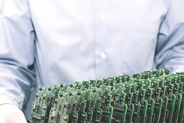 The technician takes a computer board with chips. Spare parts and components for computer equipment. Production of electronics and maintenance. The concept of high technology and robotics.