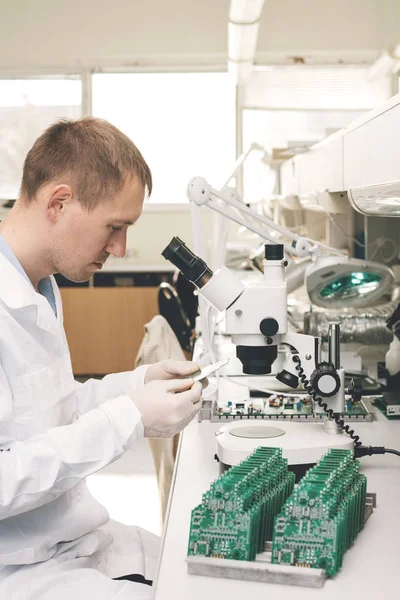 El técnico toma un tablero de computadora con chips. Piezas de repuesto y componentes para equipos informáticos. Producción de electrónica y mantenimiento. El concepto de alta tecnología y robótica . — Foto de Stock