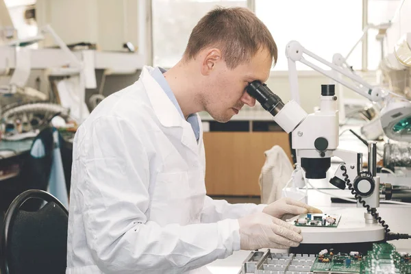 El técnico toma un tablero de computadora con chips. Piezas de repuesto y componentes para equipos informáticos. Producción de electrónica y mantenimiento. El concepto de alta tecnología y robótica . — Foto de Stock