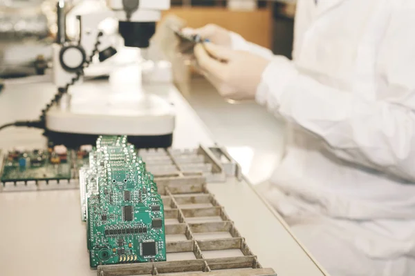 The technician takes a computer board with chips. Spare parts and components for computer equipment. Production of electronics and maintenance. The concept of high technology and robotics.