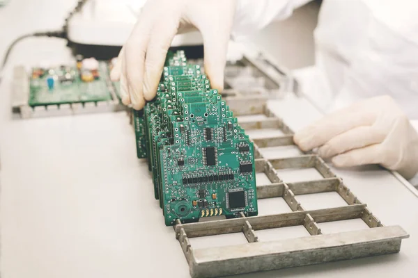 The technician takes a computer board with chips. Spare parts and components for computer equipment. Production of electronics and maintenance. The concept of high technology and robotics.