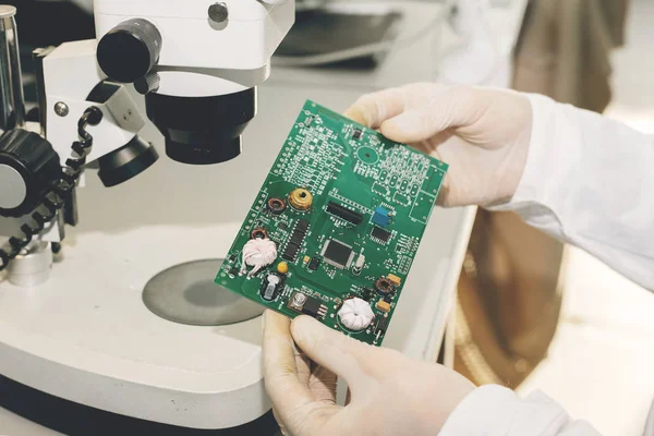 The technician takes a computer board with chips. Spare parts and components for computer equipment. Production of electronics and maintenance. The concept of high technology and robotics.