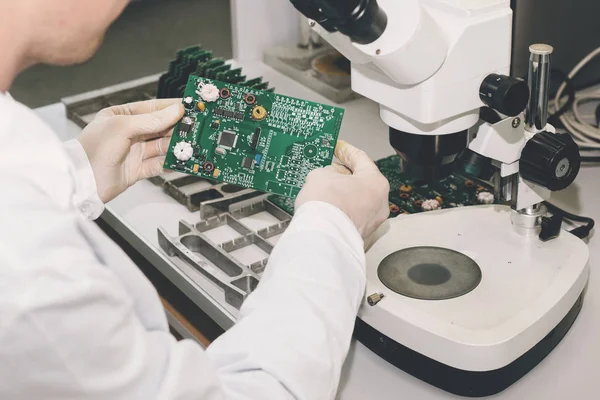 El técnico toma un tablero de computadora con chips. Piezas de repuesto y componentes para equipos informáticos. Producción de electrónica y mantenimiento. El concepto de alta tecnología y robótica . — Foto de Stock