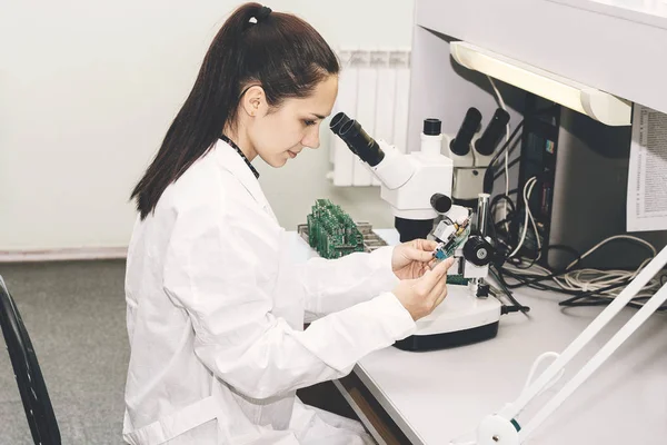 Hermosa mujer experta en informática técnica profesional examinando la computadora de a bordo en un laboratorio en una fábrica. Solución de problemas. Soporte técnico. Ingeniería. Fabricación . — Foto de Stock