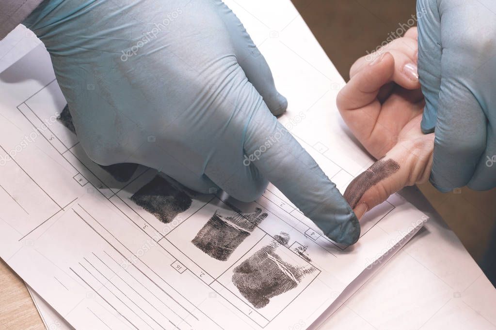 The investigation of the crime. The inspector takes fingerprints of a suspect.