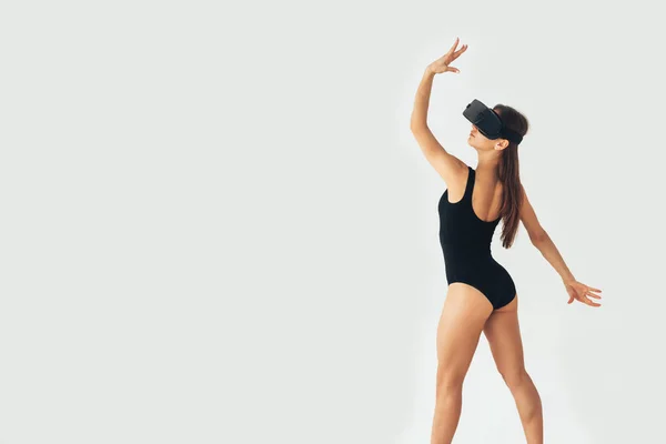Deportiva atleta chica con una hermosa figura bailando con gafas de realidad virtual. Concepto de tecnología futura. Tecnología de imagen moderna. Imagen conceptual de una danza virtual y otros deportes . —  Fotos de Stock