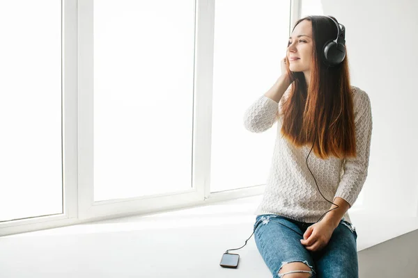 Piękna dziewczyna jest słuchanie muzyki obok okna — Zdjęcie stockowe