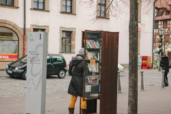 Furth, Germania, 28 dicembre 2016: Una donna sceglie un libro. Biblioteca pubblica di strada. Istruzione in Germania. Stile di vita. La vita quotidiana in Europa. Librerie . — Foto Stock