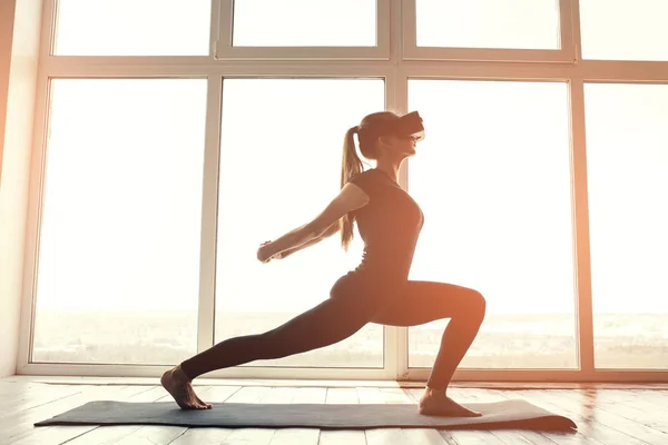 Une jeune belle femme en lunettes de réalité virtuelle fait de l'aérobic à distance. Concept technologique futur. Technologie d'imagerie moderne. Cours de sport individuel à distance . — Photo