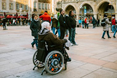 Münih, Almanya, 29 Aralık 2016: Tekerlekli sandalyede yaşlı bir kadın Münih ana Marienplatz Meydanı üzerinde manzaraları inceliyor. Turizm. Halka açık yerlerde erişim engelli insanlar için.