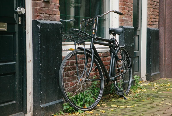 The bicycle is parked next to the house in Amsterdam in Europe. European style of life. A popular, healthy and eco-friendly means of transportation in Holland.