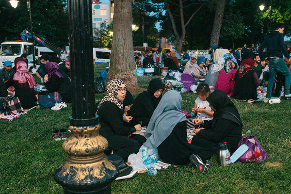 Стамбул, 16 июня 2017 года: Многие люди исламской религии принимают пищу на площади Султанахмет рядом с синей мечетью вместе со своими родственниками во время поста в Рамадан. Рамазан
.