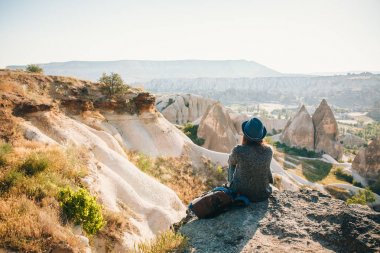 Bir gezgin bir sırt çantası ile şapkalı bir dağda duruyor ve Kapadokya Türkiye'de güzel bir görünüm bakar. Yolculuk. Hiking.