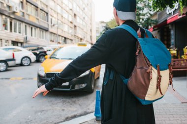 Büyük şehirde bir sırt çantası ile genç erkek turist için bir taksi bekliyor. Yolculuk. Gezi. Seyahat.