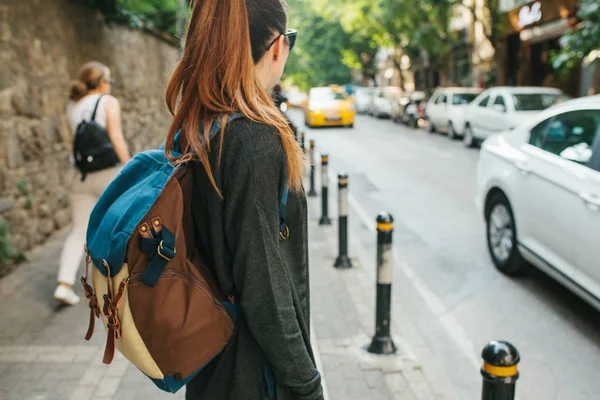 Молода туристична дівчина з рюкзаком у великому місті чекає на таксі. Подорож. Оглядова екскурсія. Подорожі . — стокове фото